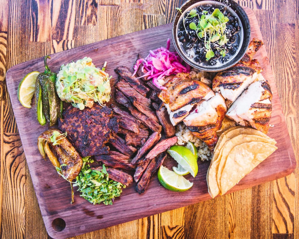 assortment of pork and other meats, spicy pepper, tortillas, limes, and pickled onion from La Luna in Chicago