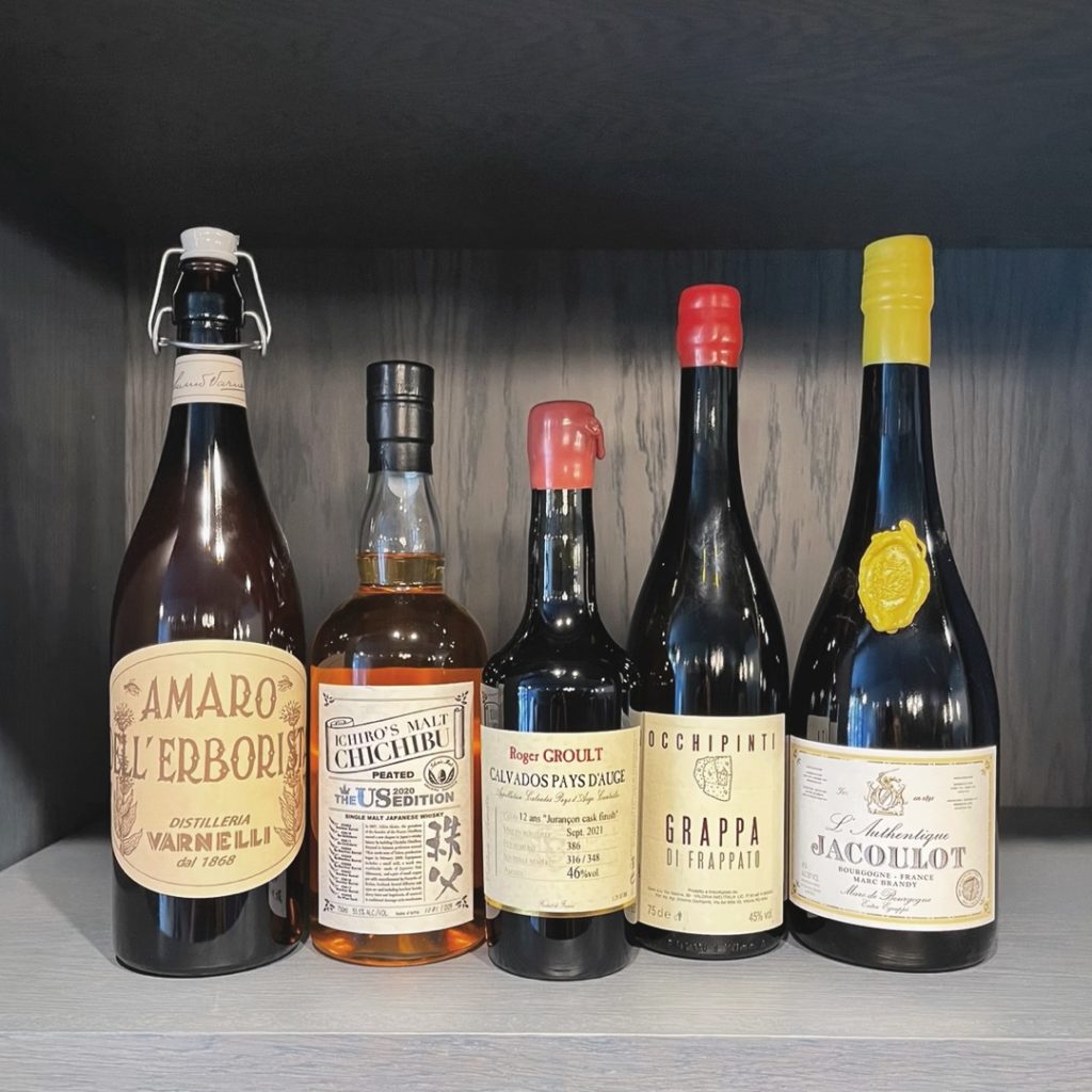 five bottles of alcohol on a shelf at Le Midi in Chicago