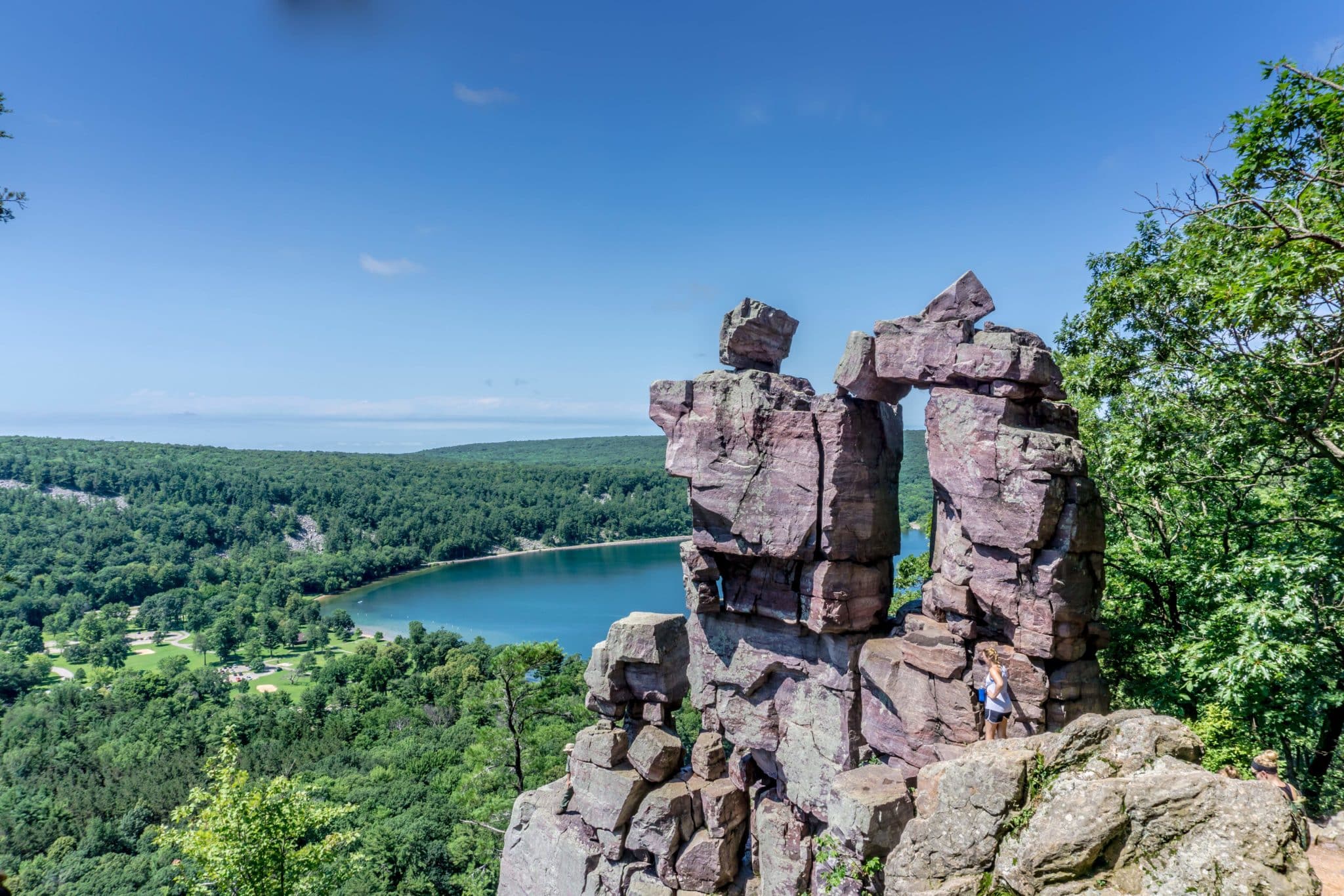 large rocks on a ledge at Devil's Lake State Park in WI with a forest and lake behind