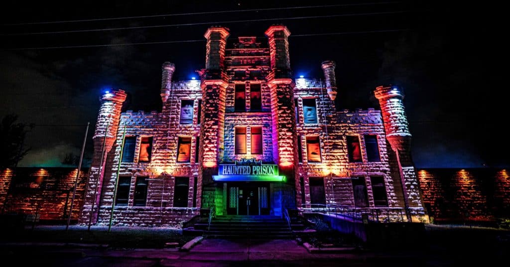 the Old Joliet Haunted Prison made of stone with a rainbow of colors on the outside of the building