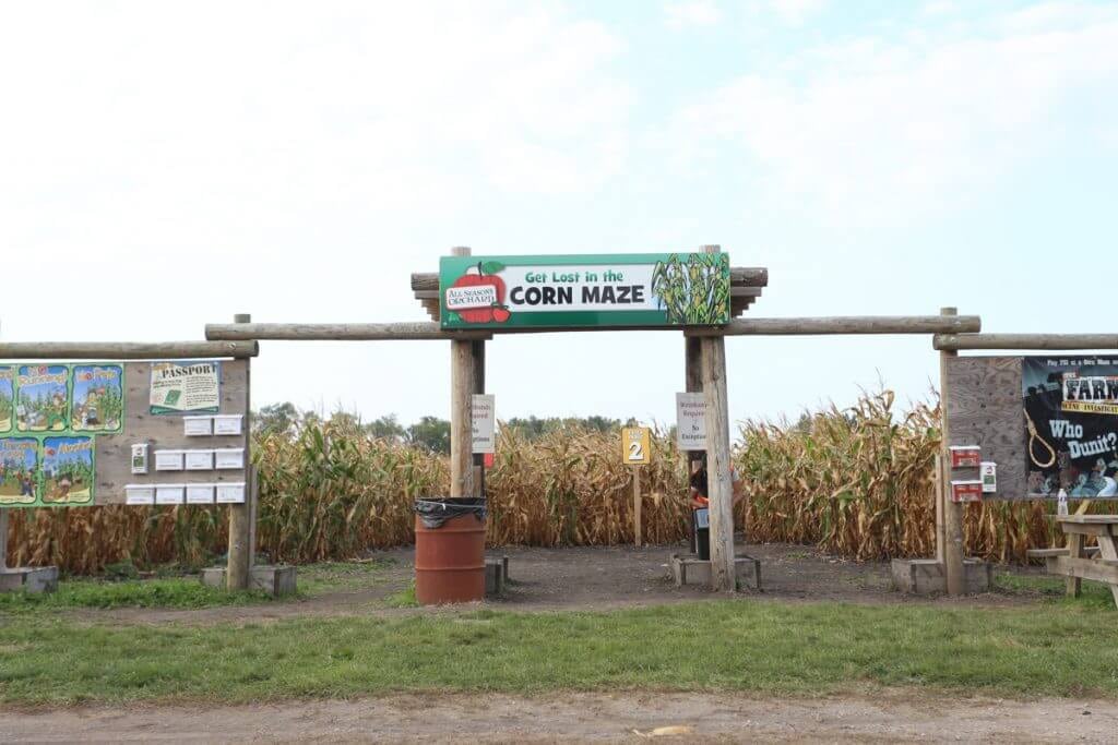 wooden entrance to one of chicago corn mazes at apple season orchard with informative bulletin boards next to the opening