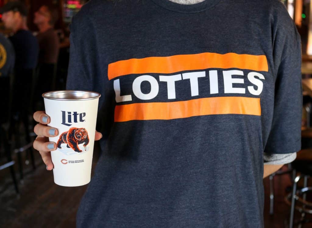 someone holding a bears cup while where a lotties pub themed bears shirt at one of chicago sports bars lottie's pub 