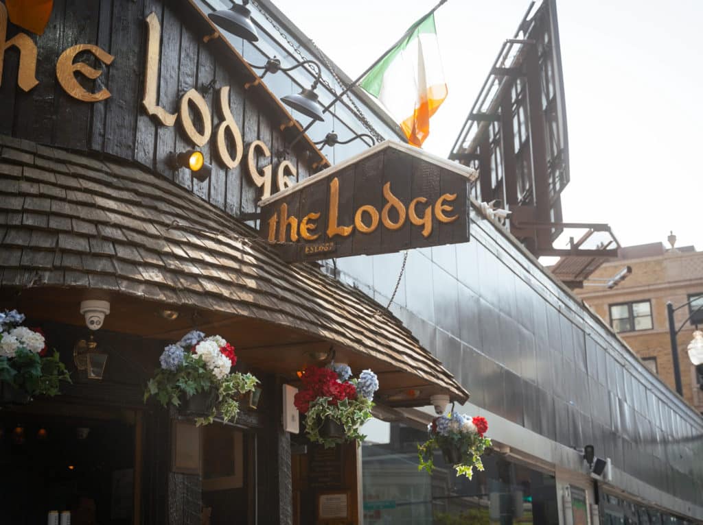 wooden structure with flowers hanging on the outside and the Flag of Ireland hanging at the lodge in Chicago