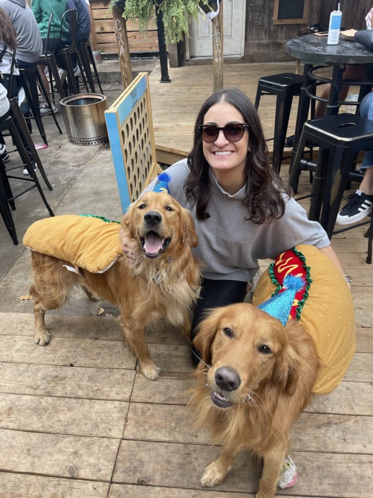 two golden retrievers dressed in hot dog costumes next to their owner at Cody's public house halloween party in chicago