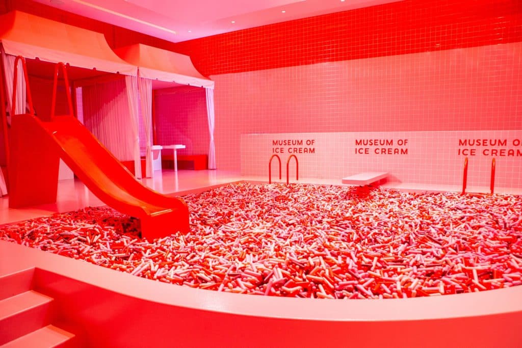 red pink and white sprinkle pool with a red slide and a red diving board at museum of ice cream in chicago