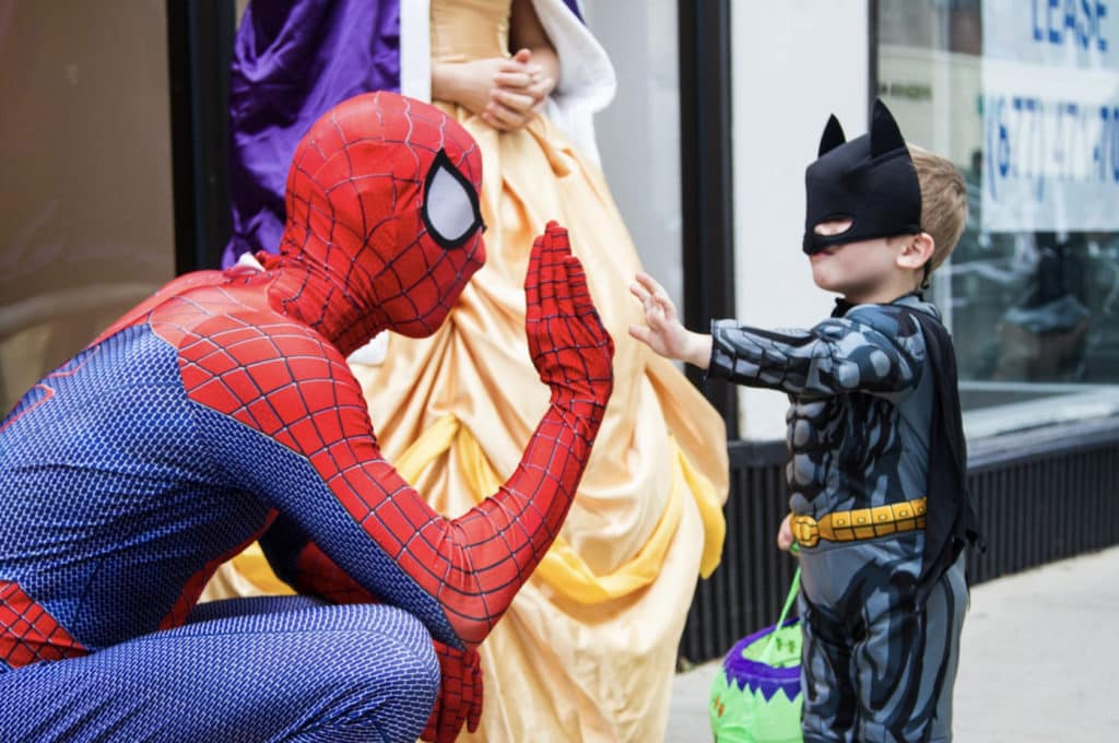 Spiderman high-fiving a kid dressed as batman during the spooktacular on clark event
