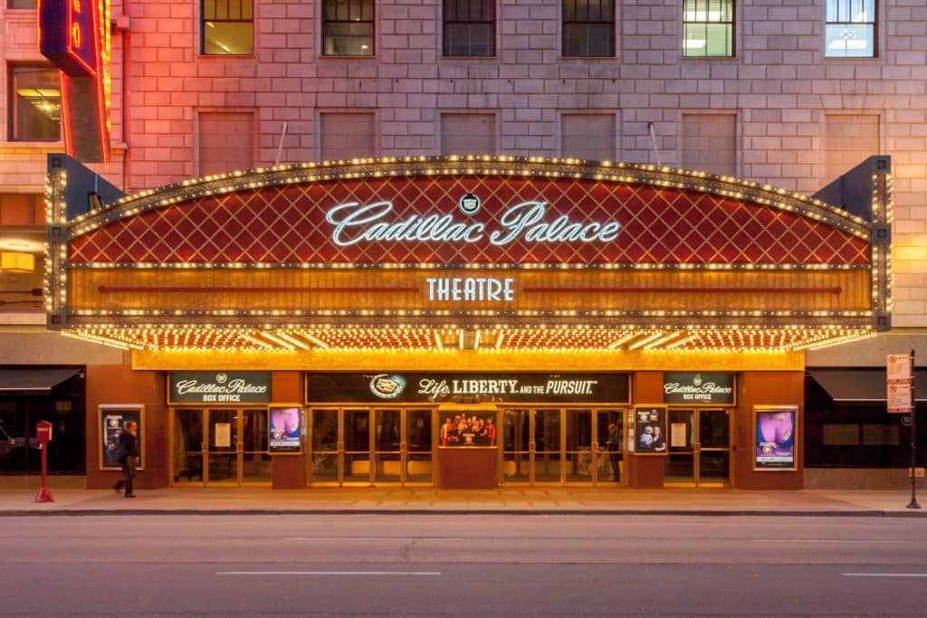 the front exterior of the The Cadillac Palace Theatre with shining lights and a red roof in chicago