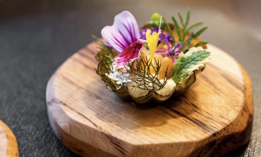a celebrated dish with flowers and garnishes on a wooden platter from the smyth in Chciago